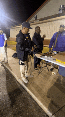 a group of men standing around a table with one man wearing a blue jacket with the word eagles on it