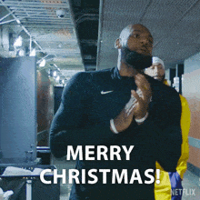 a man in a black nike shirt says merry christmas on the screen
