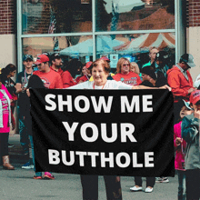 a woman holds up a black sign that says show me your butthole