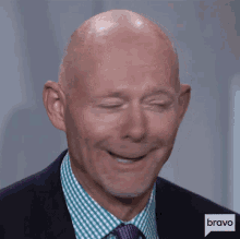 a bald man wearing a suit and tie is smiling with bravo written on the bottom