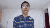 a young man wearing glasses and a patterned sweater is making a funny face .