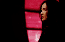 a woman in a black jacket is standing in front of a red background