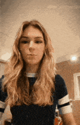 a woman with long blonde hair is standing in front of a mirror .