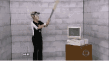 a woman is swinging a bat in front of a computer with the time 8:36