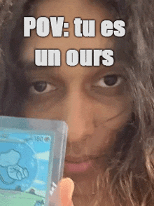a woman with long hair is holding a pokemon card in front of her face .