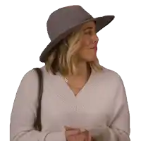 a woman wearing a hat and a sweater looks to her left