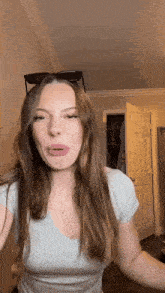 a woman wearing sunglasses and a cross necklace makes a face