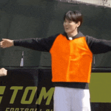 a man wearing an orange vest is standing in front of a banner that says tom