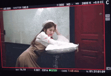 a woman is laying on a white pillow in front of a red door while a camera takes a picture of her
