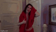 a woman wrapped in a red blanket is standing in a room .