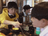 a boy in a yellow hoodie is eating a meal with chopsticks
