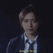 a woman in a suit and tie is laughing and says " turn the tv off "