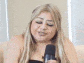 a woman is sitting on a couch holding a microphone