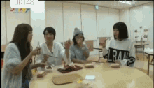 a group of young women are sitting around a table eating food with chopsticks .