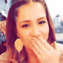 a woman is covering her mouth with her hand and wearing a ring