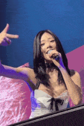 a woman in a white dress singing into a microphone with her arms outstretched