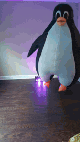 a stuffed penguin is standing on a wood floor