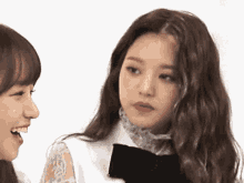 two girls are standing next to each other and looking at each other . one of the girls is wearing a bow tie .