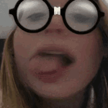 a close up of a woman wearing glasses with her tongue sticking out .