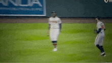 two baseball players are walking on a field .