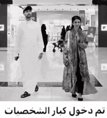 a black and white photo of a man and a woman walking in a store