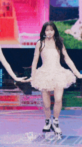 a girl in a white dress is dancing on a stage in front of a studio k sign