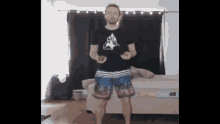 a man in a black shirt and blue shorts is juggling a ball