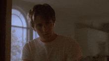 a man in a white shirt stands in a dark room