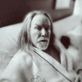 a man with long hair is wrapped in a blanket that says foster