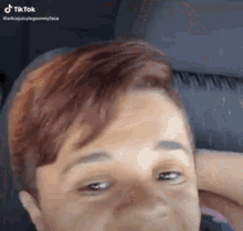 a woman with short red hair is sitting in a car .