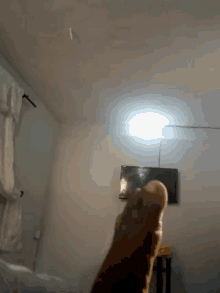 a person 's hand is reaching out towards a light in a room