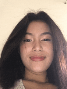 a woman with long dark hair is smiling and looking at the camera