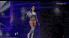 a woman is dancing on a stage in front of a wrestling logo