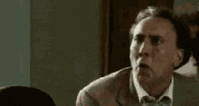 a man in a suit and tie is making a funny face while sitting in a room .