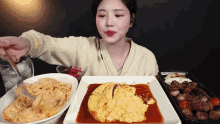 a woman is eating a plate of food with a fork and spoon