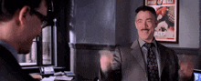 a man in a suit and tie is standing in front of a poster that says daily bugle
