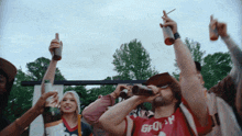 a man wearing a shirt that says gp on it is drinking from a bottle