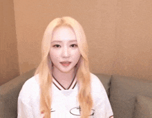 a woman with blonde hair is sitting on a couch and smiling