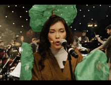 a woman singing into a microphone in front of an orchestra with the words la cumuluse soir on the bottom