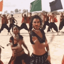 a group of people are dancing in a desert with flags .