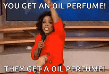 a woman in a red dress is holding a microphone and saying `` you get an oil perfume they get a oil perfume ''