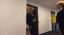 a man wearing a blue shirt with the number 1 on it walks through a hallway