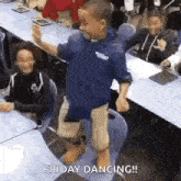 a young boy is dancing in a classroom in front of a group of students .