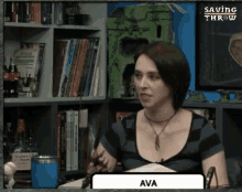 a woman is sitting at a table in front of a bookshelf with the name ava on it .