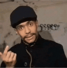 a man wearing a hat and a black jacket is giving the middle finger .
