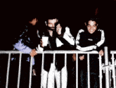 a group of people standing behind a fence with one man holding a cup that says ' supreme ' on it