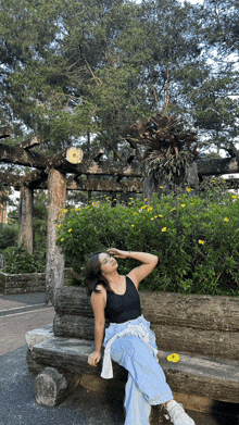 a woman is sitting on a bench in front of a tree