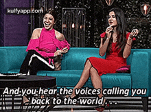 two women are sitting on a blue couch talking to each other and laughing .