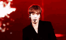 a young man wearing a microphone and a black jacket is standing on a stage .