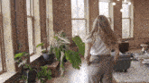 a woman is walking through a living room filled with plants